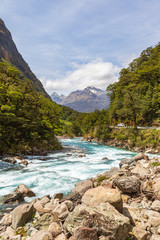 Landscape with a fast river against the background of mountains. Fiordline national park. South Island, New Zealand