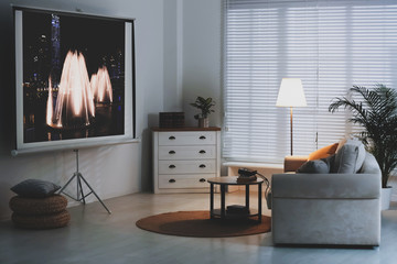 Stylish room with modern video projector and comfortable sofa