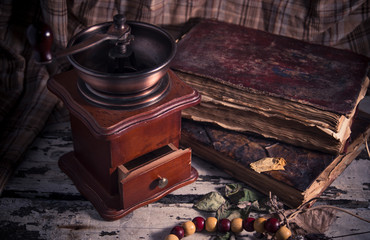 Old vintage manual coffee grinder with old books on wooden background