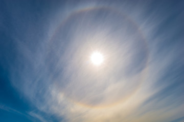 Halo around the sun. Bright colorful circular 22 degrees circle in the sky.