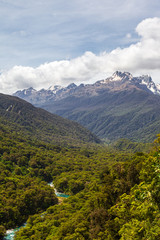Fototapeta premium Fiordland National Park. Landscapes of the South Island. View of the snow-capped mountains, dense forest and the river below. New Zealand