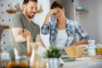 Young couple making pancakes at home. Loving couple having fun while cooking.	