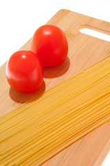 Tomatoes, spaghetti and cutting board on a white background