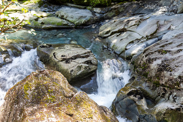 Naklejka na ściany i meble A stream disappearing into a funnel. Funnel Chasm. Fiordland in New Zealand. Stream among stones. South Island