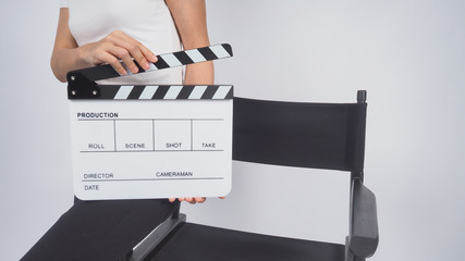 Woman is sitting on the chair and hands is holding Clapperboard or movie slate. it use in video production ,film, cinema industry on white background.