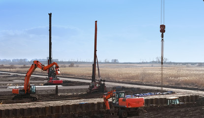 Naklejka premium construction site with construction machines an excavator and piling machine that level the ground and drive piles