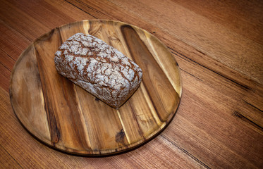 Grain bread loaf on a wooden tray. The bread is isolated on the tray