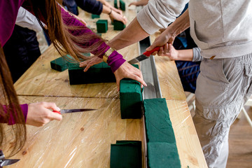Hand of the wedding decorator in the process of work. Green fresh flowers,pruning shears ,sponge flowers .