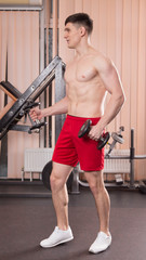 Fototapeta premium Young man flexing muscles with barbell in gym.