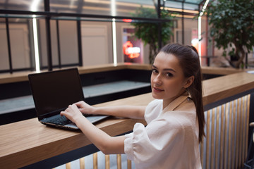 Lifestyle portrait in the interior. A young woman works at a laptop in a coworking,