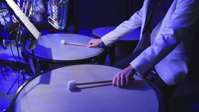 a man plays a drum kit, a musician performs a part on timpani