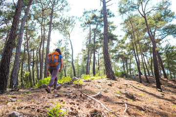 A girl with a backpack goes along a mountain trail.