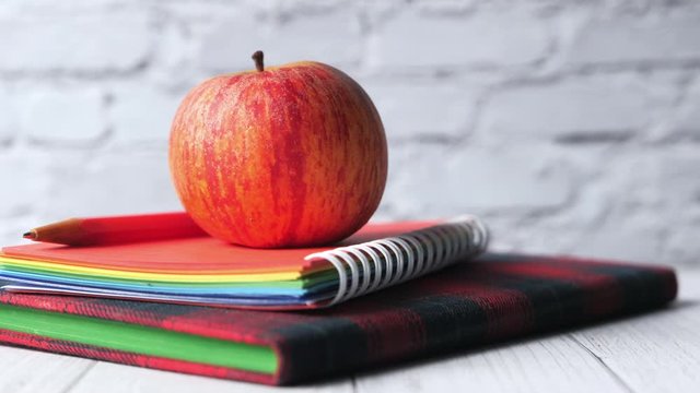close up of apple on stack of notebooks on table.