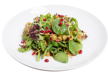Spinach and pomegranate salad in the white plate.