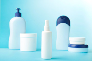 Different cosmetic bottles on blue background. Top view