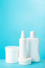 White cosmetic bottles on blue background. Top view