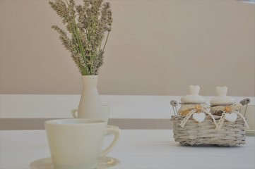 bouquet of lavender flowers in vase and tea cupin white table back yard