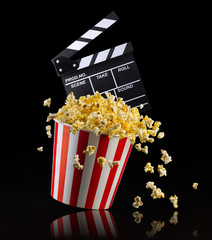 Flying popcorn and film clapper board isolated on black background