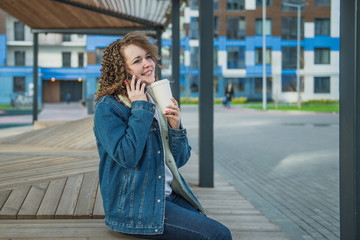 Fototapeta premium Happy girl sitting in the yard of the house and drinking coffee from a Cup