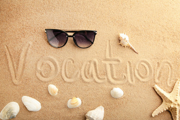 Fototapeta na wymiar The inscription Vocation and beach accessories on the sandy beach. Summertime