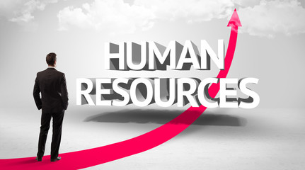 Rear view of a businessman standing in front of HUMAN RESOURCES inscription, successful business concept