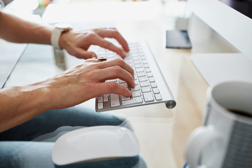 Woman's hands typing on a keyboard. Side view close up