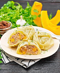 Manty with meat and pumpkin in plate on black wooden board