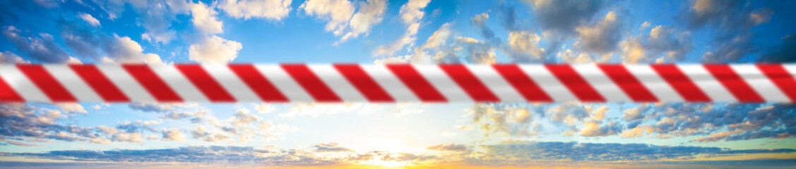 Prohibition and quarantine concept. Beautiful sky clouds with red warning tape