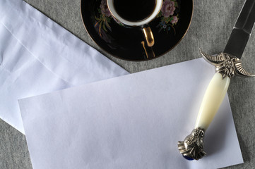 Open letter, blank sheet, paper knife and coffee.