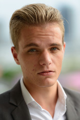 Obraz premium Face of young handsome blond businessman in suit outdoors