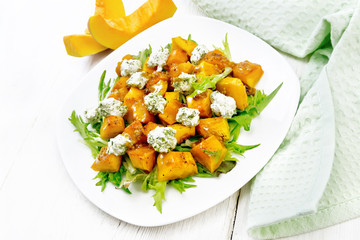 Salad of pumpkin and cheese in plate on light board