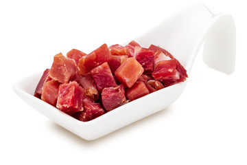 Iberian ham (serrano) cut into cubes (diced). In porcelain bowl. Isolated on white background.