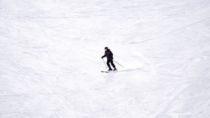 Full length of skier skiing on fresh powder snow. Man skier running downhill on sunny Alps slope