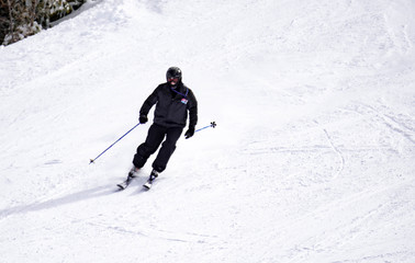 Full length of skier skiing on fresh powder snow. Man skier running downhill on sunny Alps slope