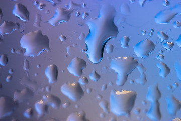 Large drops of rain on the glass in summer weather