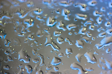 Large drops of rain on the glass in summer weather