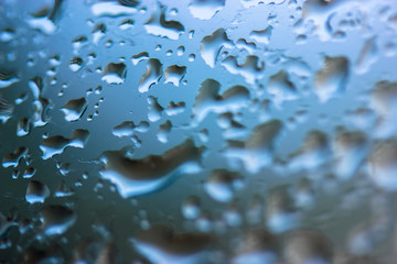 Large drops of rain on the glass in summer weather