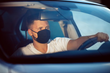 Man driving a car wearing on a medical mask during an epidemic, a driver in a mask, protection from the virus. Coronavirus, disease, infection, quarantine, covid-19, pandemic, epidemic concept