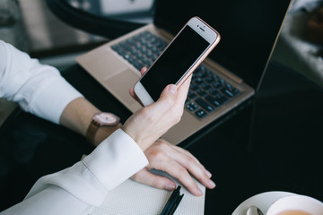 Faceless female using cellphone and sitting at table