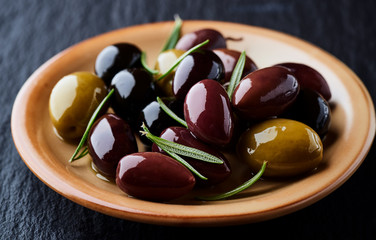 Various olives on black stone background. Close up.