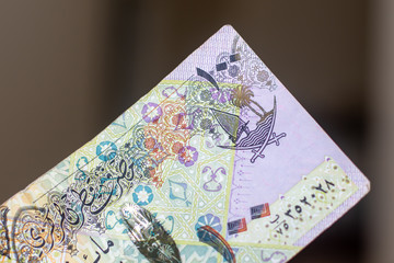 Currency of the Qatar - purple one hundred rial or riyal notes spread out on a brown background. Money exchange.