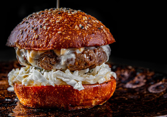 Traditional beef burger with vegetables on dark background