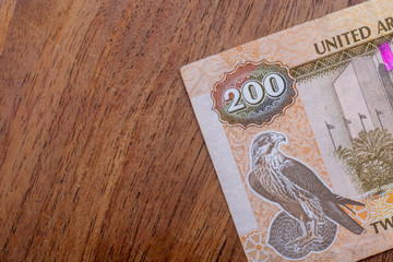 The Currency of the United Arab Emirates (UAE) - Close up of a two hundred Dirham note  on a brown table background. Money exchange.