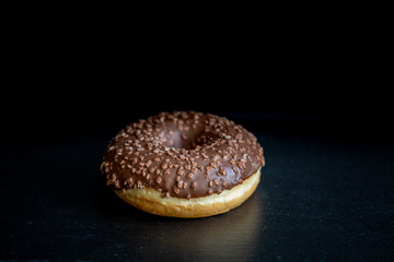 Sweet donut on black background. Tasty, fresh sprinkled donut