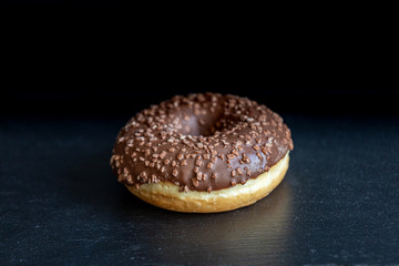 Sweet donut on black background. Tasty, fresh sprinkled donut