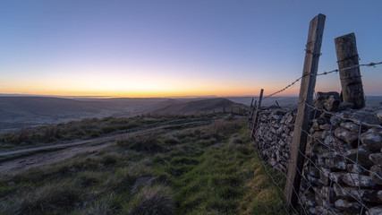 Peak District National Park landscape view with old wooden farm fence and stone wall at dawn