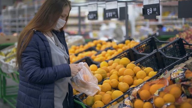 a woman buys oranges at a grocery hypermarket