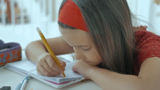 joven con la cabeza apoyada en la mesa escribe los deberes del colegio