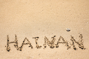 Word Hainan written in the sand seashore of tropical beach in Hainan Island China with authentic coral stone. Copy space for text