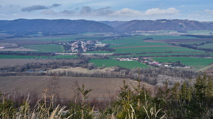 Old railway viaduct in green vale with hilly forested landscape in the background, Jezernicky...